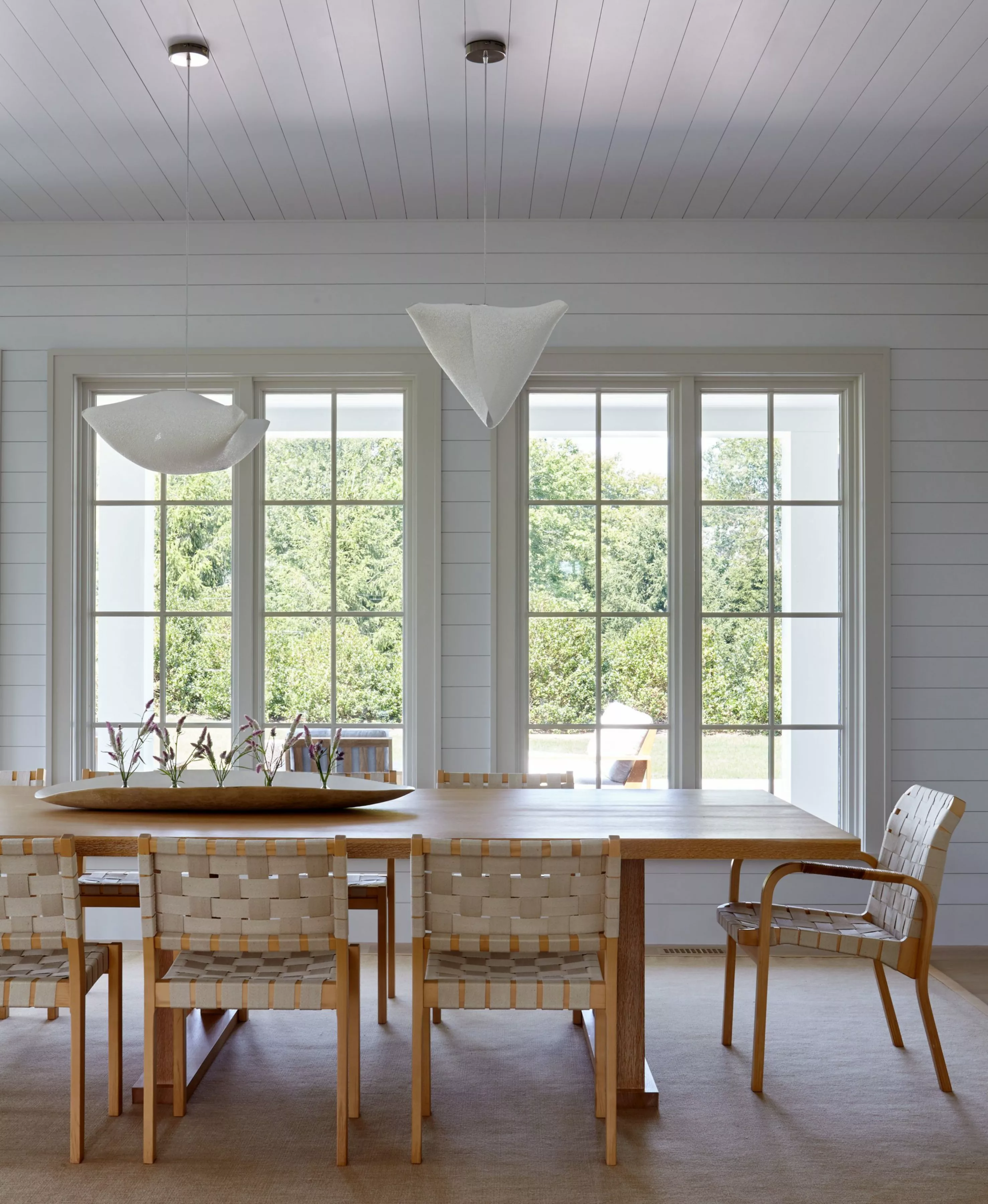 Dining room in a beach house with organic shaped pendants and wood and woven fabric chairs