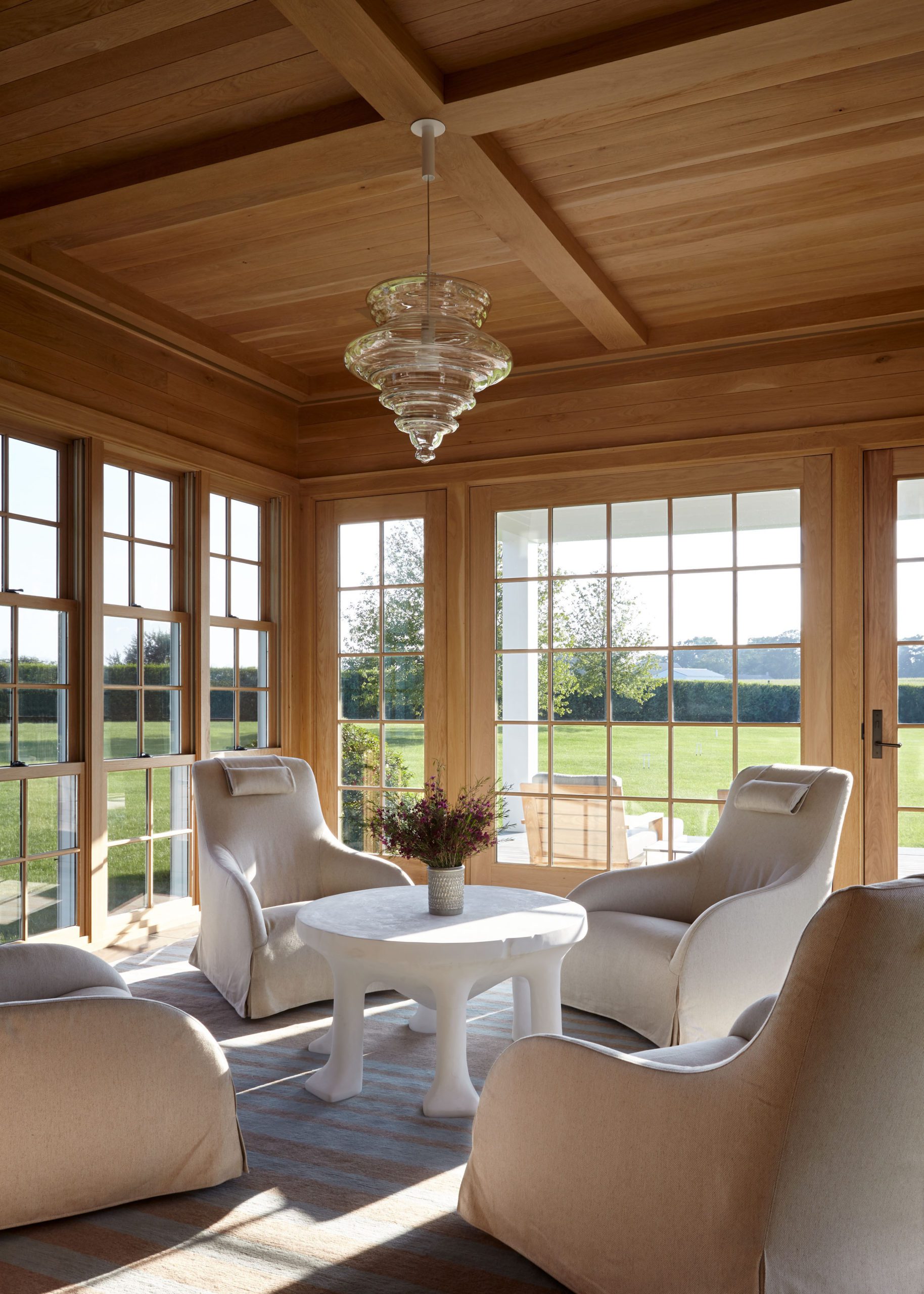 wood lined sunroom with views to landscape of grass and trees