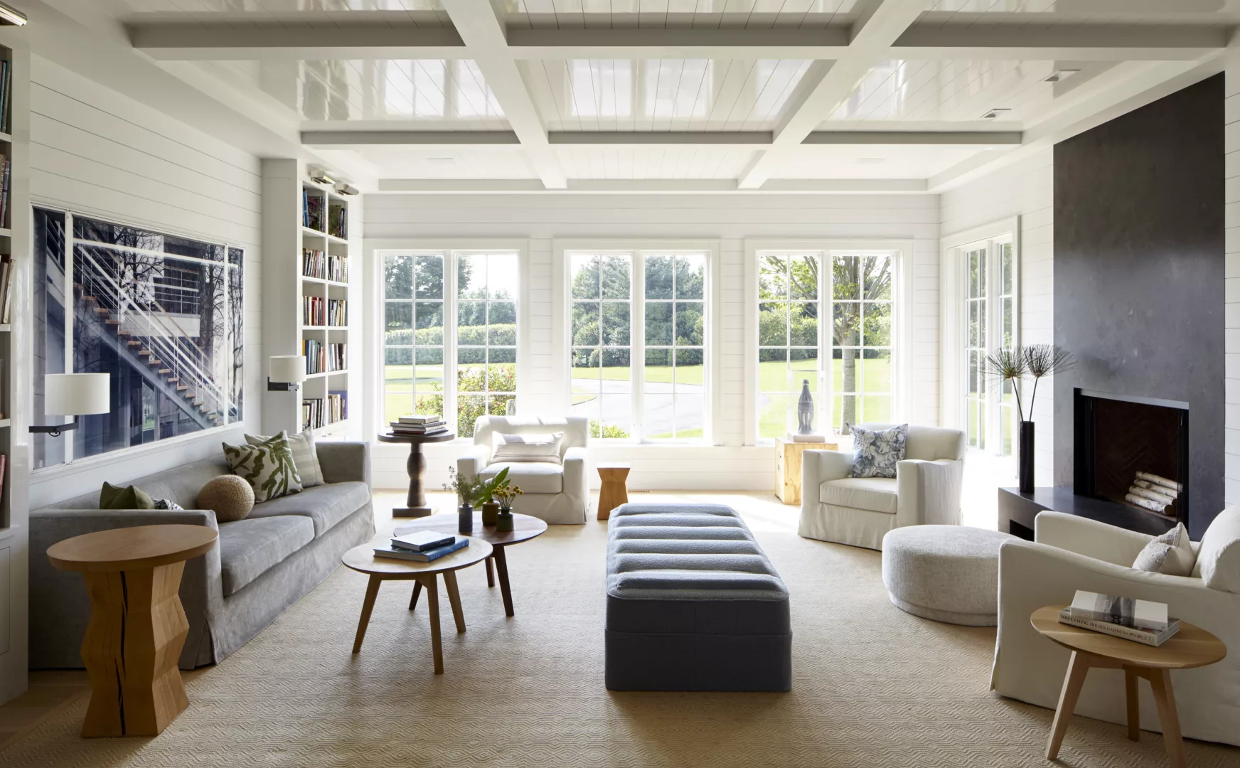 living room with glossy white ceiling and two furniture groupings with a center ottoman